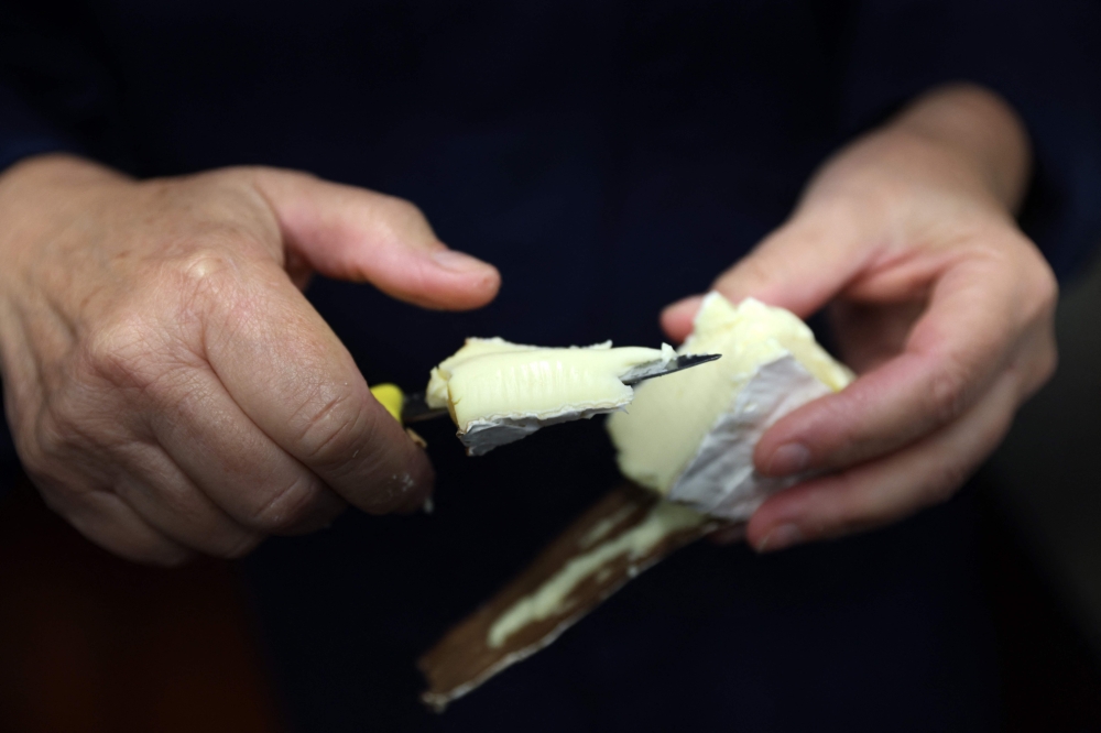 Stacey Hedges, Owner and Founder of Hampshire Cheese Company cuts a Tunworth cheese to sample at the Hampshire Cheese Company near Basingstoke in Hampshire south east England, on March 14, 2023. — AFP pic