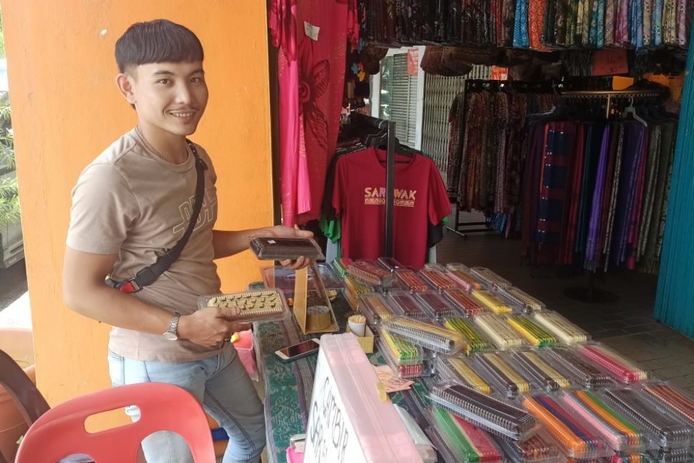 Mohd Farizan shows the variety of Kek Lapis available at his stall along Kuching Waterfront. — Borneo Post Online pic