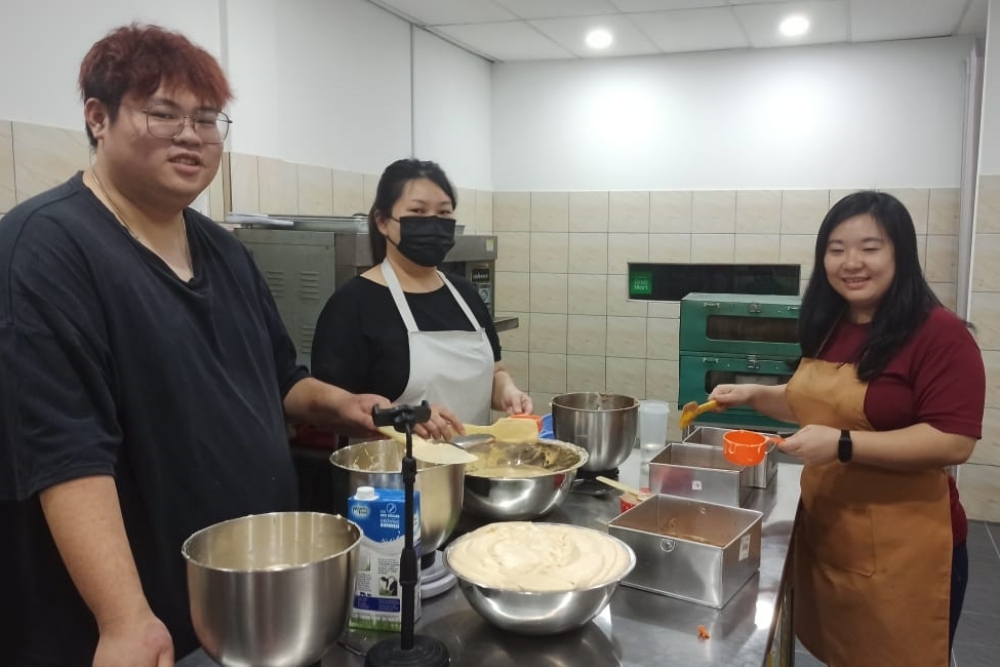 Chai (right) makes a batch of Kek Lapis with her staff Chong Jia Neng (left) and Karen Lau. — Borneo Post Online pic