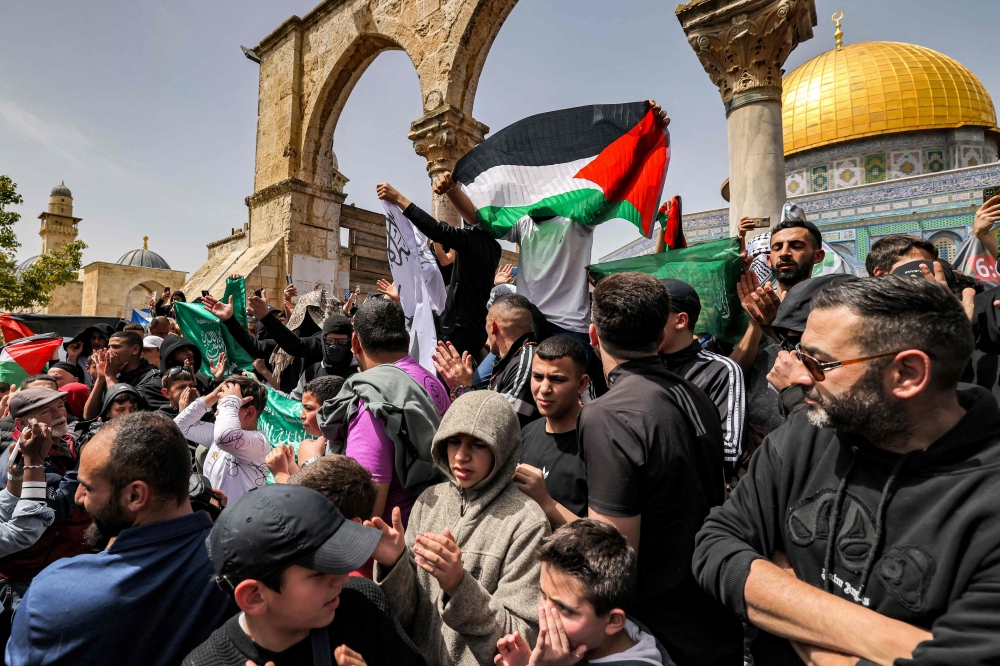 A man holds up a paper Palestinian flag outside the Dome of the Rock shrine at al-Aqsa mosque compound in the Old City of Jerusalem on April 7, 2023 on the third Friday Noon prayer during the Muslim holy fasting month of Ramadan. — AFP pic