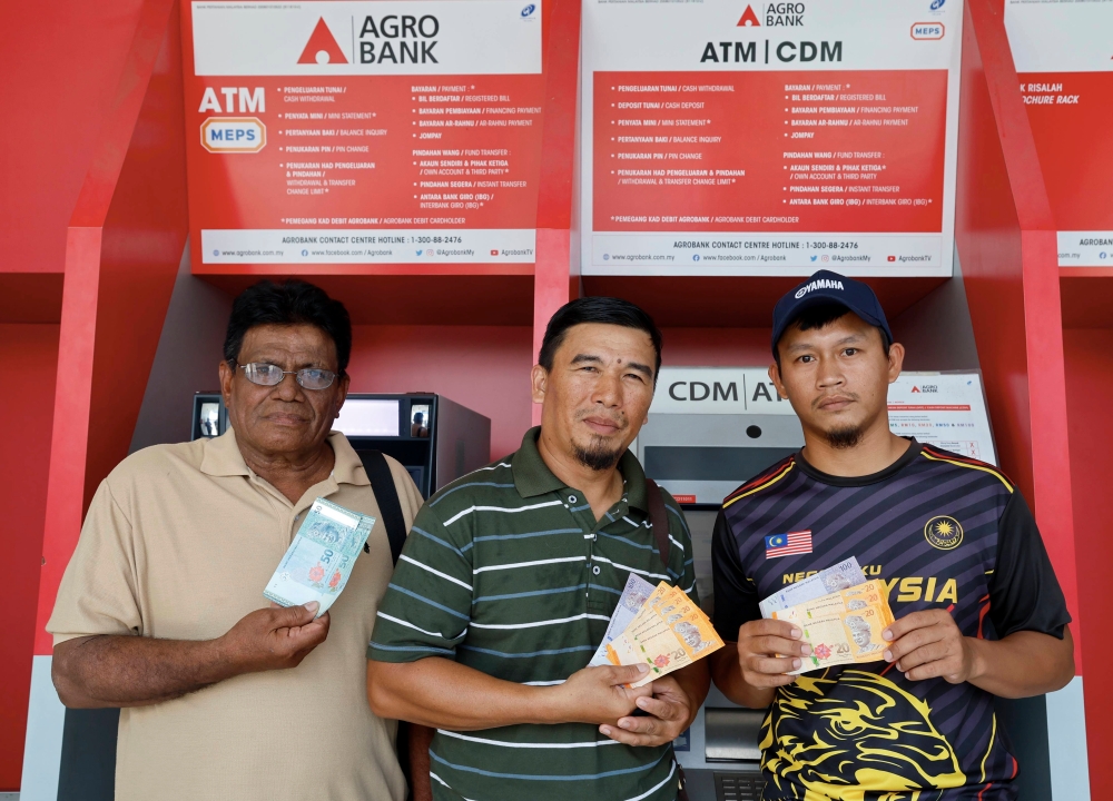 (From left) Fishermen Razak Yusoff, 66, Jamsari Ramsah, 44, and Muhammad Nor Hafiz Azizis, 32, show the Special Aidilfitri Financial Assistance of RM200 after withdrawal in Tanjong Karang, Kuala Selangor April 10, 2023. — Bernama pic