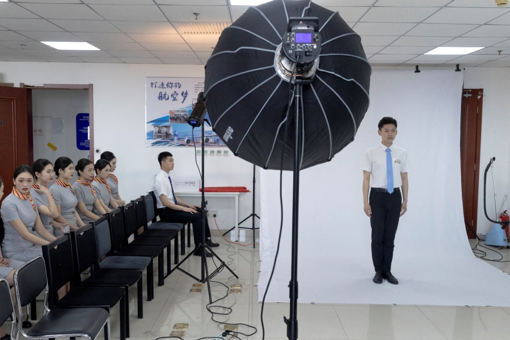 An applicant has his picture taken during a recruiting session for cabin crew jobs at Hainan Airlines in Beijing March 30, 2023. — Reuters pic
