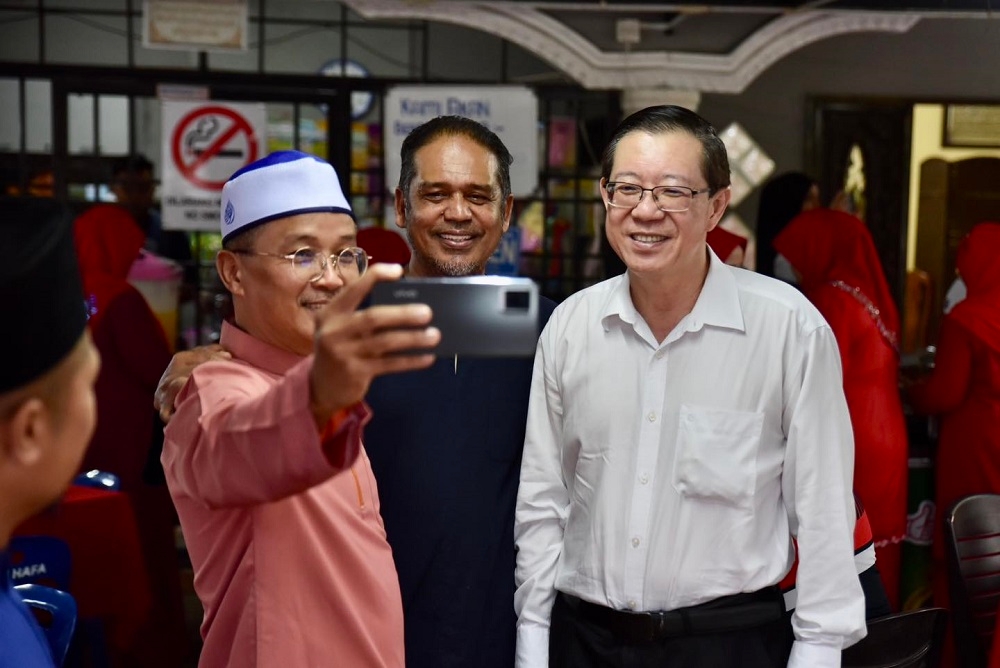 DAP chairman Lim Guan Eng poses for a picture with attendees during Umno’s Balik Pulau division porridge distribution and breaking fast event in Penang April 11, 2023. — Picture via Facebook/Lim Guan Eng