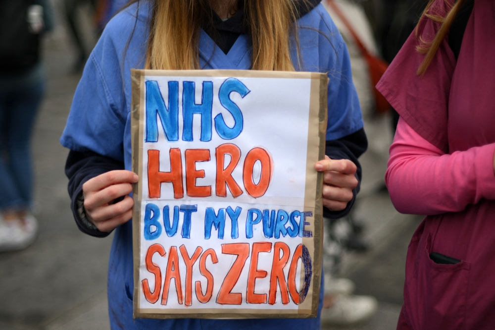 A demonstrator holds up a placard during the protest during what has been billed as the most disruptive strike in its history, in a dispute over pay and working conditions. — AFP pic