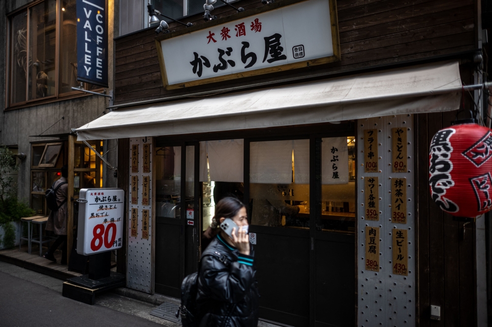 This picture taken on March 1, 2023 shows a pedestrian walking past an izakaya bar in Tokyo. — AFP pic