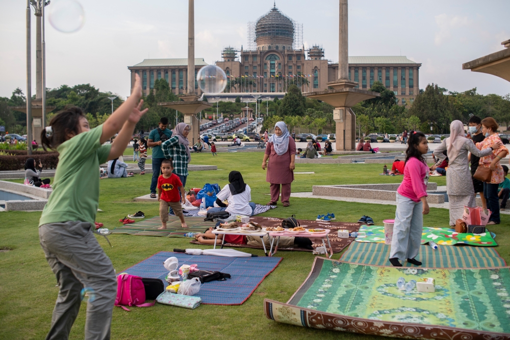 Visitors to Putrajaya fill up their time while waiting to break fast during Ramadan in Dataran Putra at Precinct 1, with the Perdana Putra building in the background. — Picture by Shafwan Zaidon