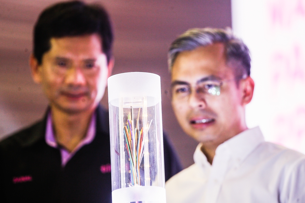 Communications and Digital Minister Fahmi Fadzil (right) together with TIME dotCom Executive Director Datuk Zainal Amanshah Zainal Arshad (left) looks a fibre-optic cable at the PPR/PA @MyKabel Unity Package project launch at PPR Kerinchi in Kuala Lumpur April 14, 2023. — Picture by Hari Anggara 