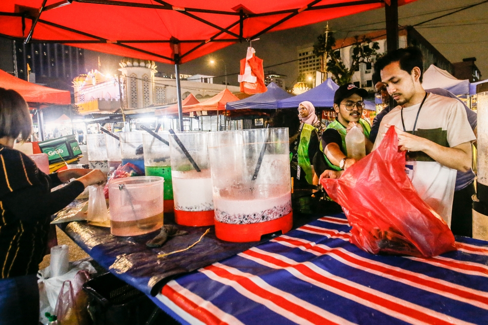 Volunteers from Gema coax traders to donate unsold food and drinks for MySaveFood collection at Kampung Baru Ramadan Bazaar in Jalan Raja Alang April 12, 2023. — Picture by Hari Anggara