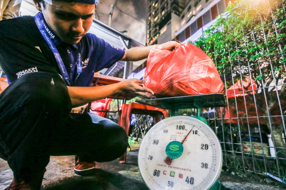 A Gema volunteer weighs the food and drinks collection at Kampung Baru Ramadan Bazaar in Jalan Raja Alang, before they are repackaged and redistributed to the needy April 12, 2023. — Picture by Hari Anggara