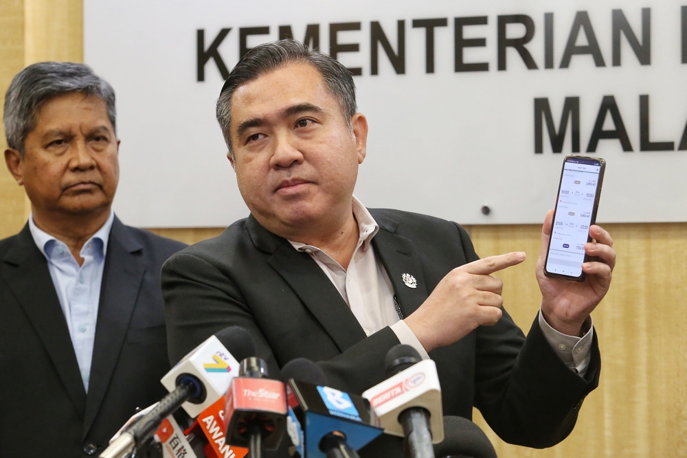 Transport Minister Anthony Loke showing off the MAS airline app on his phone for the price of flight tickets from KL to Tawau during the press conference at the Ministry of Transport April 17, 2023. — Picture by Choo Choy May