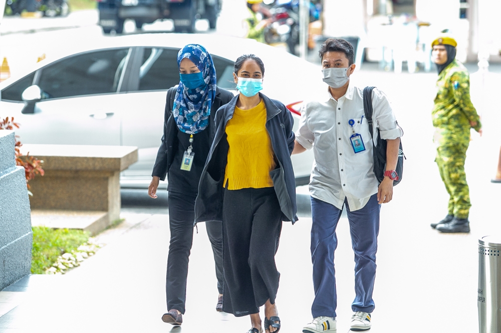 Siti Nuramira Abdullah is escorted by plain cloth police officer at the Kuala Lumpur High Court complex July 13, 2022. — Picture by Devan Manuel