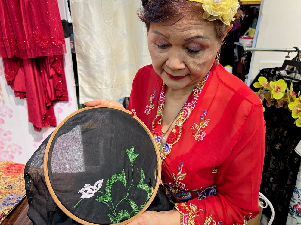 Cecelia shows the cloth stretched on a frame before embroidering.  — Picture by Opalyn Mok