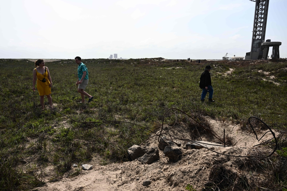 A piece of concrete (R foreground) blown off the launch pad  (R rear) litters the ground on April 22, 2023, after the SpaceX Starship lifted off on April 20 for a flight test from Starbase in Boca Chica, Texas. — AFP pic