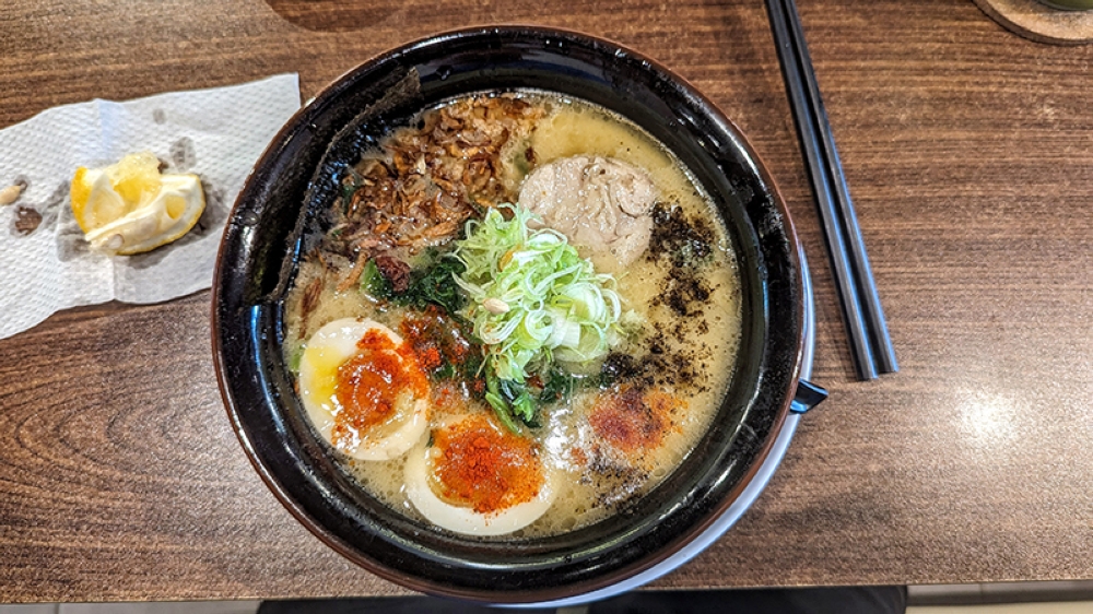 Toripaitan Extreme Ramen, with the complete works from the squeezed lemon wedge and topped with tableside condiments of chilli and black garlic powder.