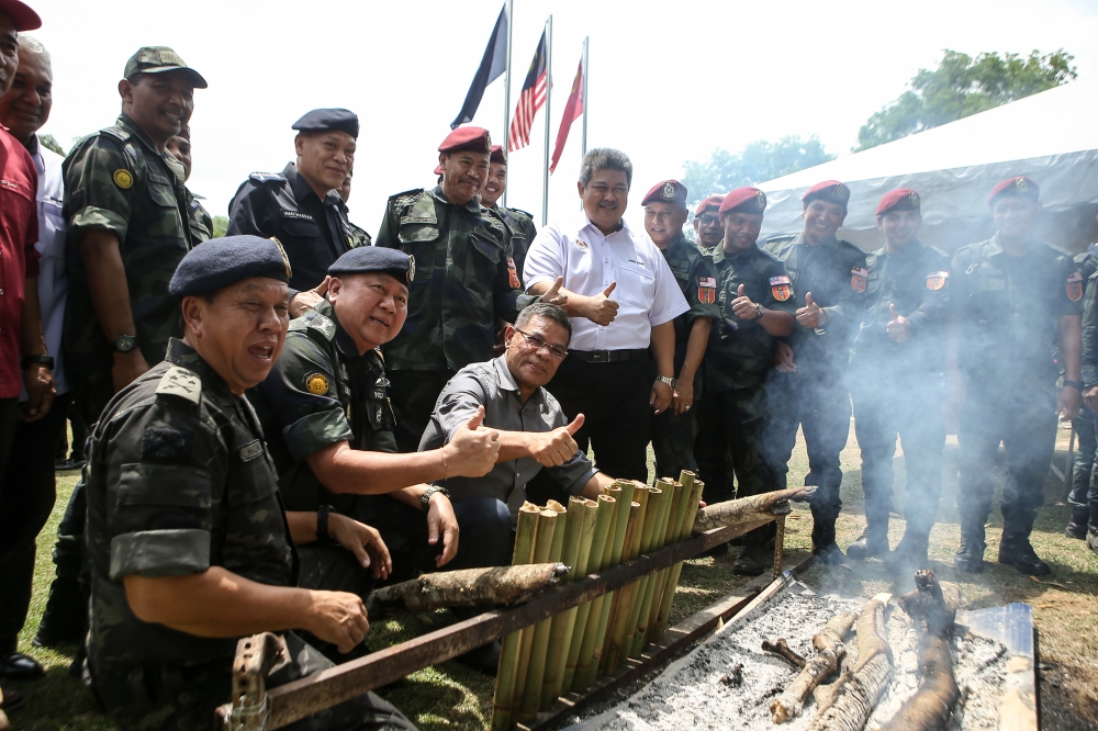 Home Minister Datuk Seri Saifuddin Nasution Ismail watches as General Operations Force (PGA) personnel make lemang during a visit to the Tactical Camp (Martak PGA) at Bukit Kayu Hitam April 25, 2023. — Bernama pic