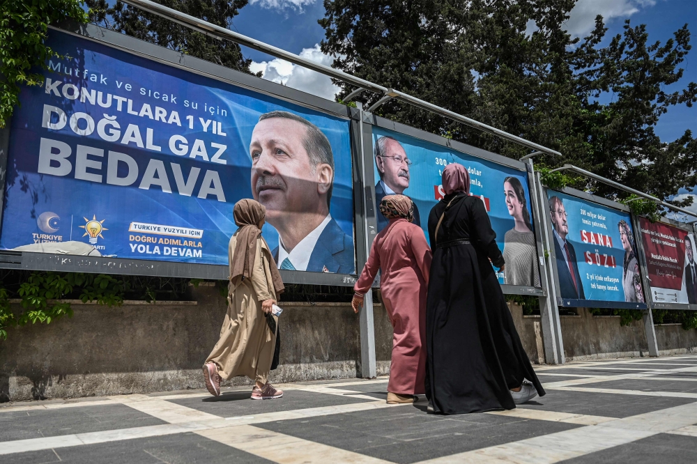 Women walk next to billboards, one reading ‘1 year free natural gas in residences’ with the portrait of Turkish President Recep Tayyip Erdogan (left) and  another with the portrait of Republican People’s Party (CHP) leader and presidential candidate, Kemal Kilicdaroglu (3rd right) reading ‘promise to you’, in Sanliurfa, south-eastern Turkey on April 28, 2023. ― AFP pic