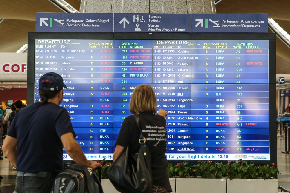 2023 年 1 月 10 日，旅客在雪邦吉隆坡国际机场查看信息飞行板。 — 照片作者 Yusof Mat Isa