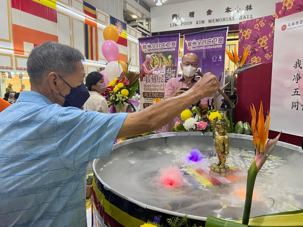 A devotee bathes the Buddha statue at the Malaysian Buddhist Association in George Town. — Picture by Opalyn Mok