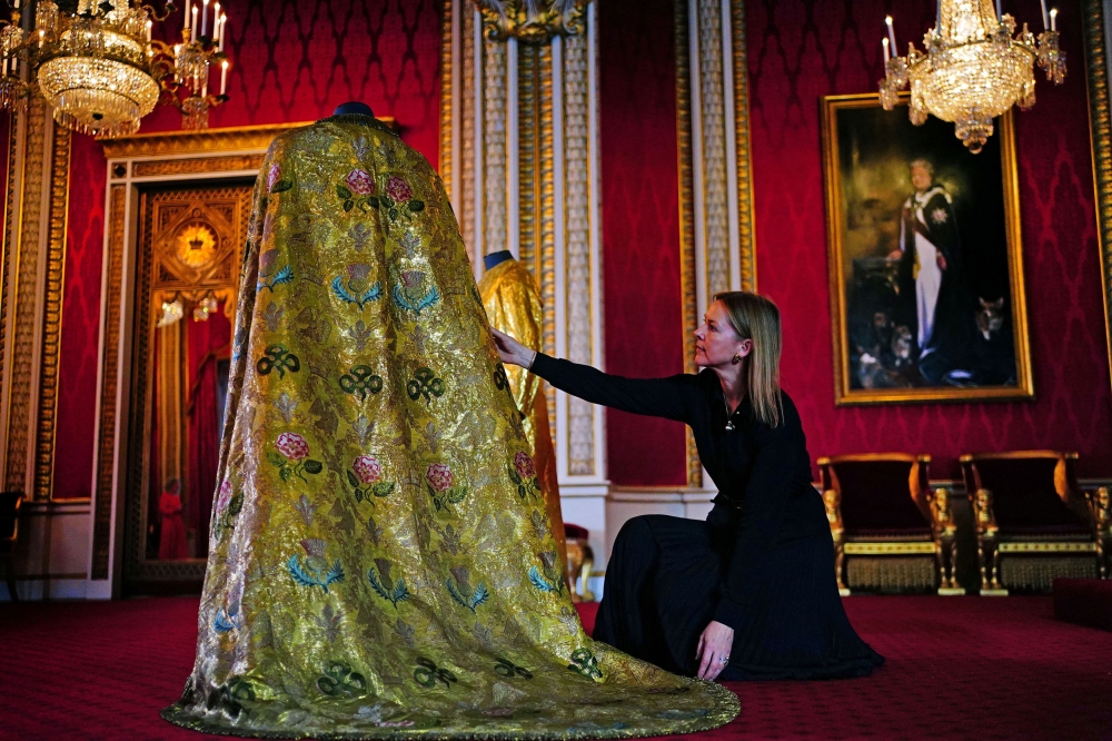 Caroline de Guitaut, deputy surveyor of the King’s Works of Art for the Royal Collection Trust, adjusts the Imperial Mantle, which forms part of the Coronation Vestments and will be worn by Britain’s King Charles during his coronation at Westminster Abbey, in the Throne Room at Buckingham Palace, London April 26, 2023. — Picture by Victoria Jones/Pool via Reuters
