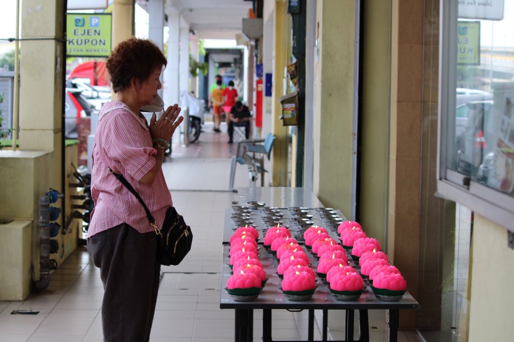 A devotee prays outside the temple with her mask removed. Outdoor masking was made optional on May 1, 2022. — Picture courtesy of Ti-Ratana Buddhist Society