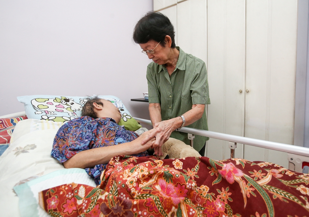 Retired nurse Juliana Koh Choy Fong attending to her daughter Ng Poh Anne, who suffers from brain tumour. — Picture by Farhan Najib