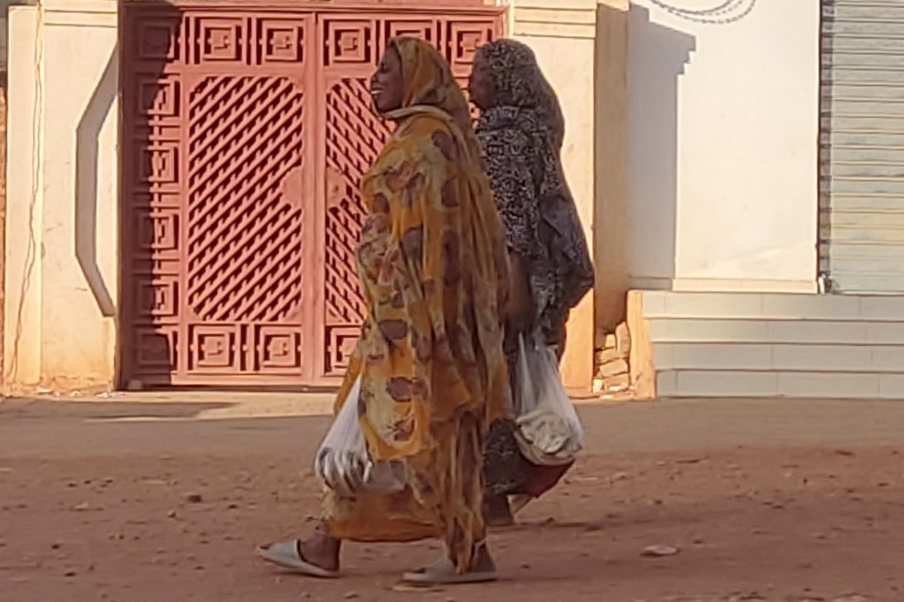 Women carrying their shopping walk on an almost empty street in southern Khartoum, on May 2, 2023. — AFP pic