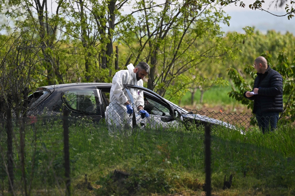 A forensic investigator works at one of the crime scenes, outside of the village of Dubona near the town of Mladenovac, about 60 kilometres south of Serbia’s capital Belgrade, on May 5, 2023, in the aftermath of a drive-by shooting. — AFP pic