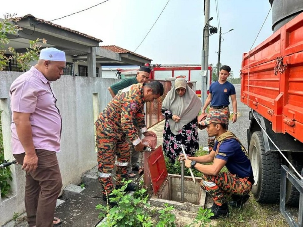 Rantau Panjang MP Datuk Siti Zailah Mohd Yusoff (third from right) has come under public backlash after sharing on her Facebook page pictures and an account of how she channelled water from a hydrant to residents in Kelantan hit by water supply problems during the current heatwave. — Picture via Facebook/Siti Zailah