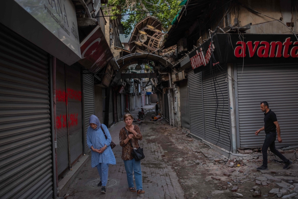 Pedestrians walk through a market where most shops are closed due to the earthquake damage in Hatay, a city which suffered the most damage in the earthquakes that occurred in southern Turkey, on May 12, 2023. — AFP pic