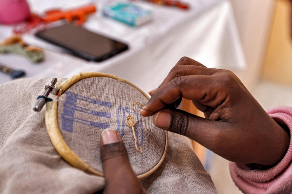 In this picture taken on February 23, 2023 a worker sews a pattern of ancient Egyptian hieroglyphs on a cloth at the Malaika Linens factory. — AFP pic
