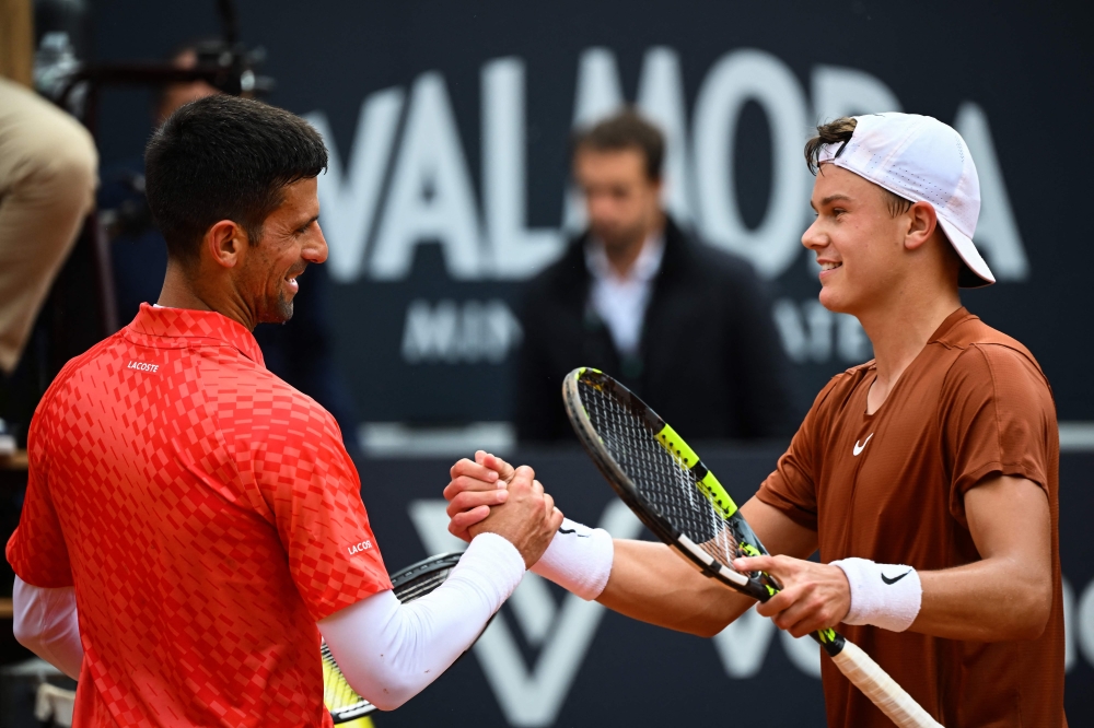 Denmark's Holger Rune (right) and Serbia's Novak Djokovic shake hands after Rune won their quarterfinals match of the Men's ATP Rome Open tennis tournament at Foro Italico in Rome May 17, 2023. — AFP pic