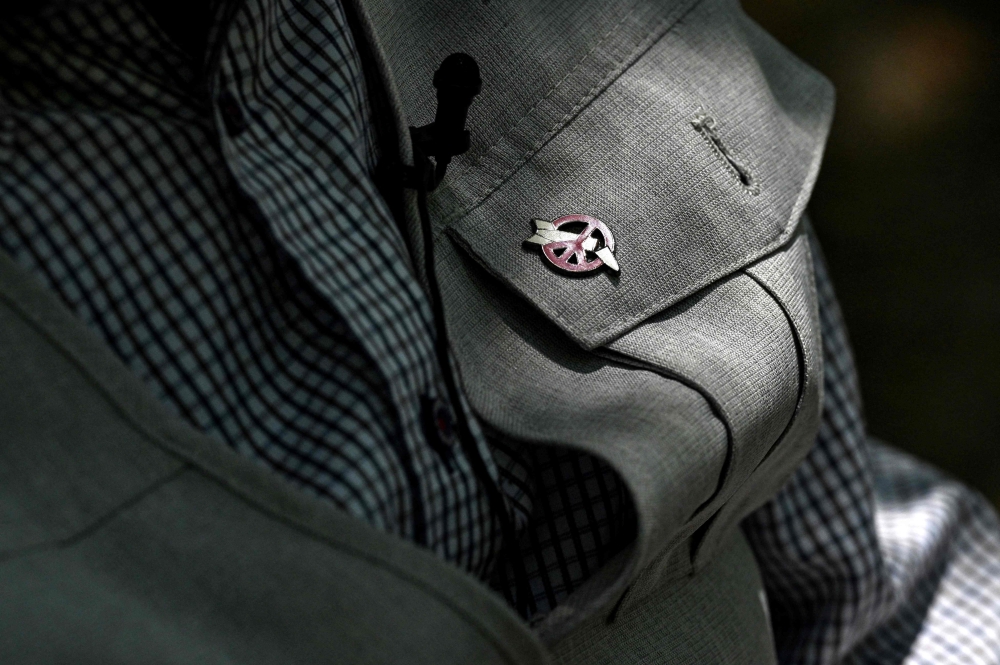 An anti-nuclear symbol pinned on the jacket of 82-year-old atomic bomb survivor Masao Ito. — AFP pic
