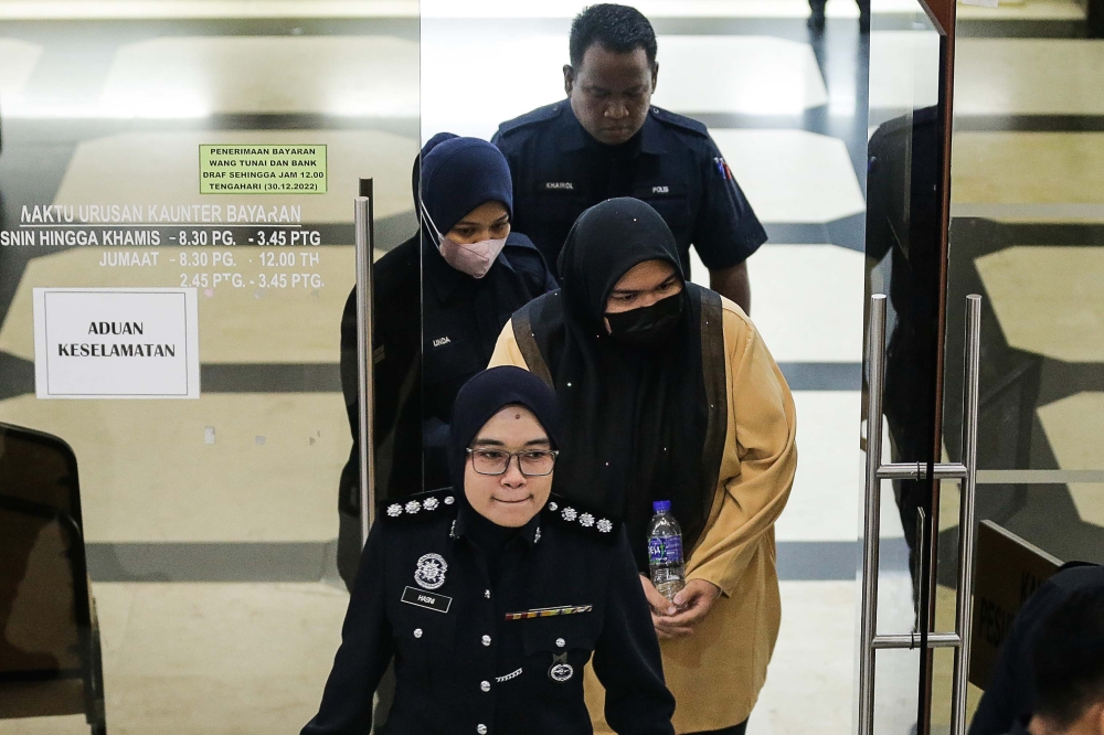 Rumah Bonda founder Siti Bainun Ahd Razali being escorted by a police officer after receiving a 12 years jail sentence, at Kuala Lumpur Court Complex, May 3, 2023. — Picture by Sayuti Zainudin