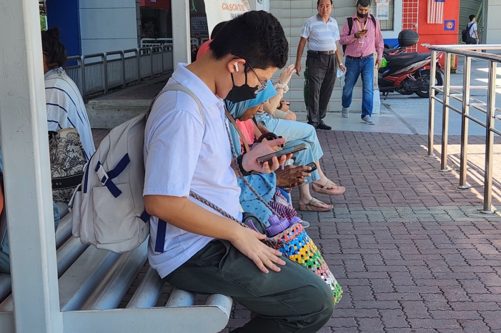 A student is seen carrying a two-litre water bottle while waiting for the Rapid KL bus in Taman Jaya LRT Station. May 18, 2023. — Picture by Shathana Kasinathan
