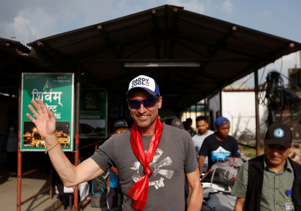 British climber Kenton Cool, 49, waves towards the media personnel, upon his arrival at the airport, as he returns after completing his 17th ascent of Mount Everest, which is the most by any foreign climber, in Kathmandu, Nepal May 19, 2023. ― Reuters pic