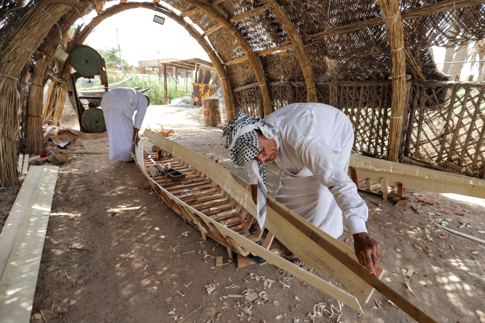 In this picture taken on April 29, 2023, a carpenter measures a plank as he builds a traditional 
