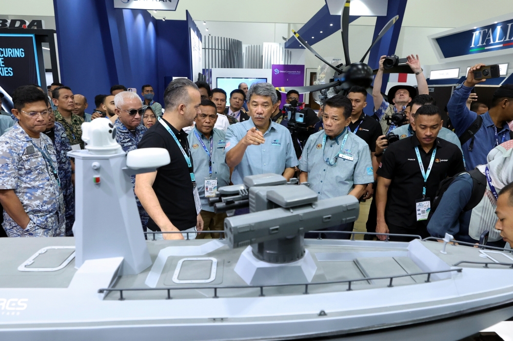 Defence Minister Datuk Seri Mohamad Hasan (centre) listens to a briefing by Turkiye’s Meteksan Savunma Sanayii AA director Burak Akbas (3rd left) on the ‘ULAQ Scout Ship’ model at the Lima ‘23 maritime segment exhibition site at Resort World Langkawi May 22, 2023. — Bernama pic