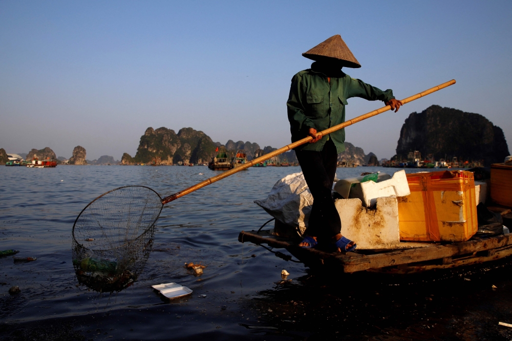 This photo taken on May 17, 2023, shows a worker picking up trash from Ha Long Bay in northeast Vietnam. — AFP pic