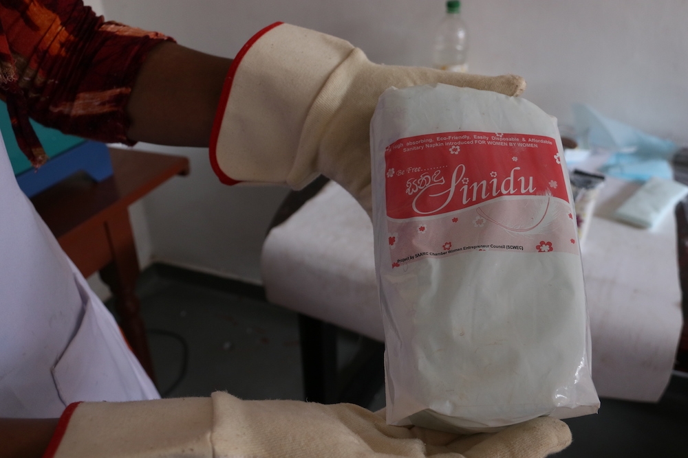 File photo of a woman displaying a packet of sanitary pads at the Sinidu Factory in Kithulwatte, Colombo March 13, 2019. - Thomson Reuters Foundation pic