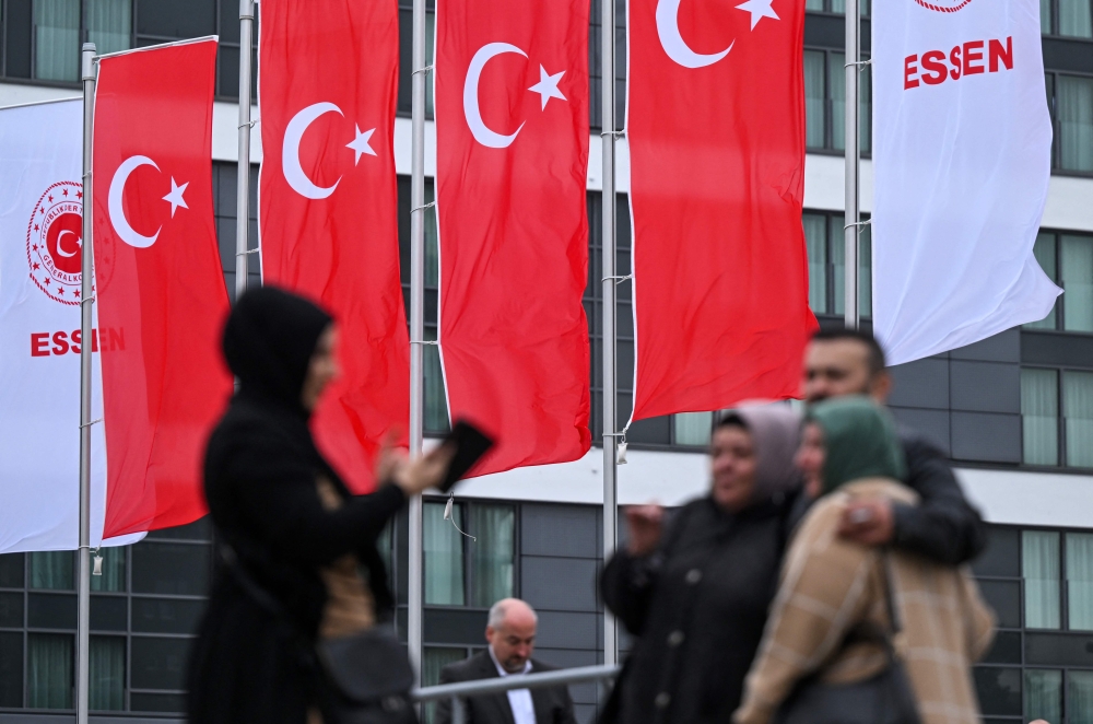 Turkish voters living in Germany take pictures of themselves in front of Turkish flags outside a polling station set up in the Grugahalle hall in Essen, western Germany, on May 23, 2023, ahead of Turkey’s first run-off election to take place on May 28, 2023. — AFP pic