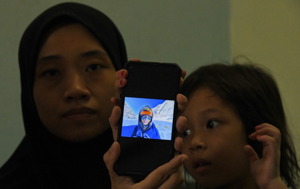 Muhammad Hawari Hashim’s wife, Saffiyah Tang Xie Li, 34, and his oldest child Hana Sakeena Muhammad Hawari Hashim, four, show a picture of Hawari at Mount Everest when met at their home in Kepala Batas  May 28, 2023. — Bernama pic