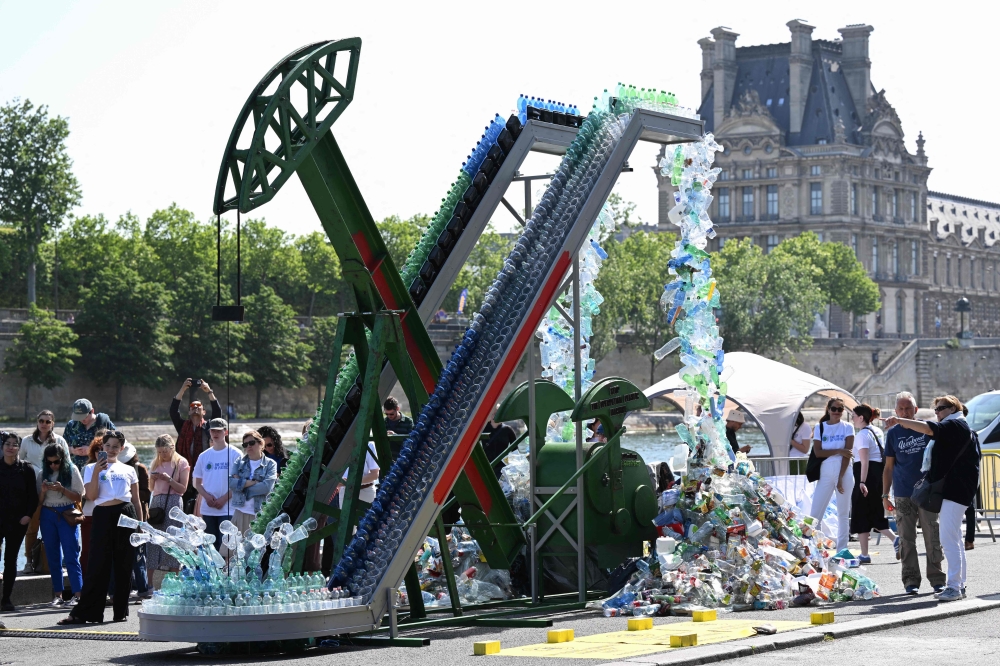 Guests stand next to Canadian artist and activist Benjamin Von Wong's 5-metre tall art installation the ‘PerpetualPlastic Machine’ during its unveiling ceremony on the banks of the Seine River in Paris on May 27, 2023, for the Global Plastics Treaty to stop runaway plastic and use. — AFP pic