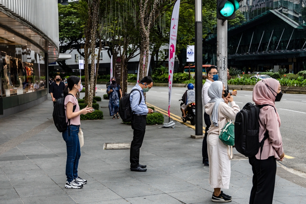 People wait to cross the street during the morning rush hour in Kuala Lumpur October 5, 2022. The majority of Malaysian millennials (30 per cent) and Gen-Zs (28 per cent) preferred having full freedom to choose whether to work from home or on-site. — Picture by Firdaus Latif
