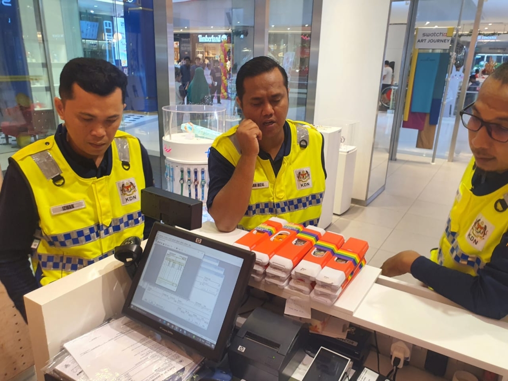 Home Ministry officers with seized Swatch watches at Sunway Putra Mall. — Picture courtesy of Swatch