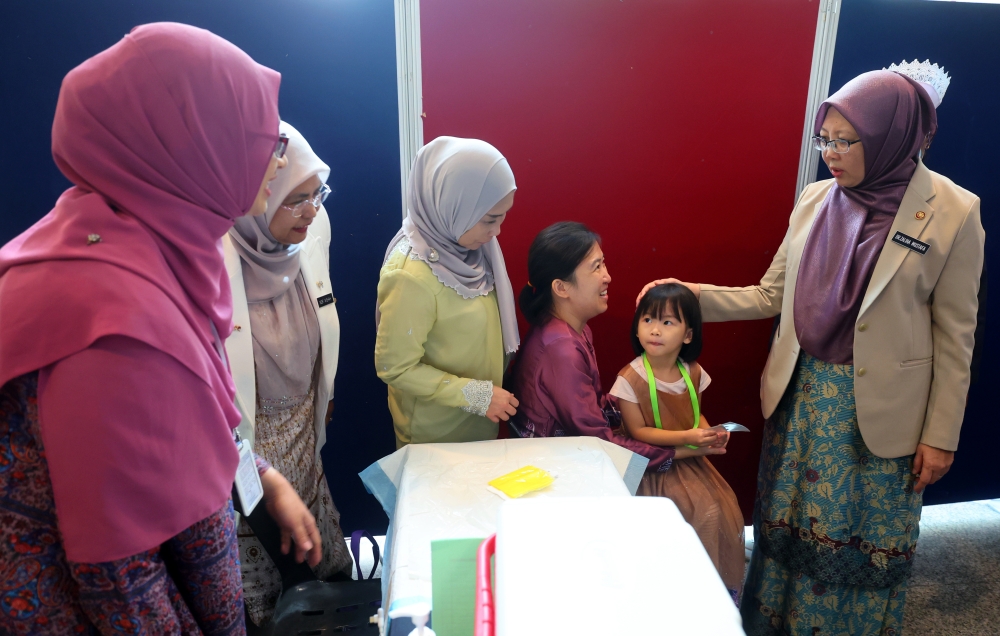 Health Minister Dr Zaliha Mustafa (right) speaks to the parent of a child receiving the free pneumococcal vaccination at the National-Level Immunisation Day 2023 celebration in Putrajaya May 31, 2023. — Bernama pic