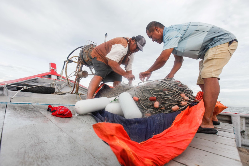 Fishermen Lim Kee Hwa (left) and Teo Kun Chui (right) prepare their nets to cast into the sea. — Picture by Sayuti Zainudin