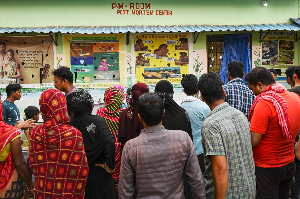 Family members wait outside a post mortem centre in search of their loved ones. — AFP pic