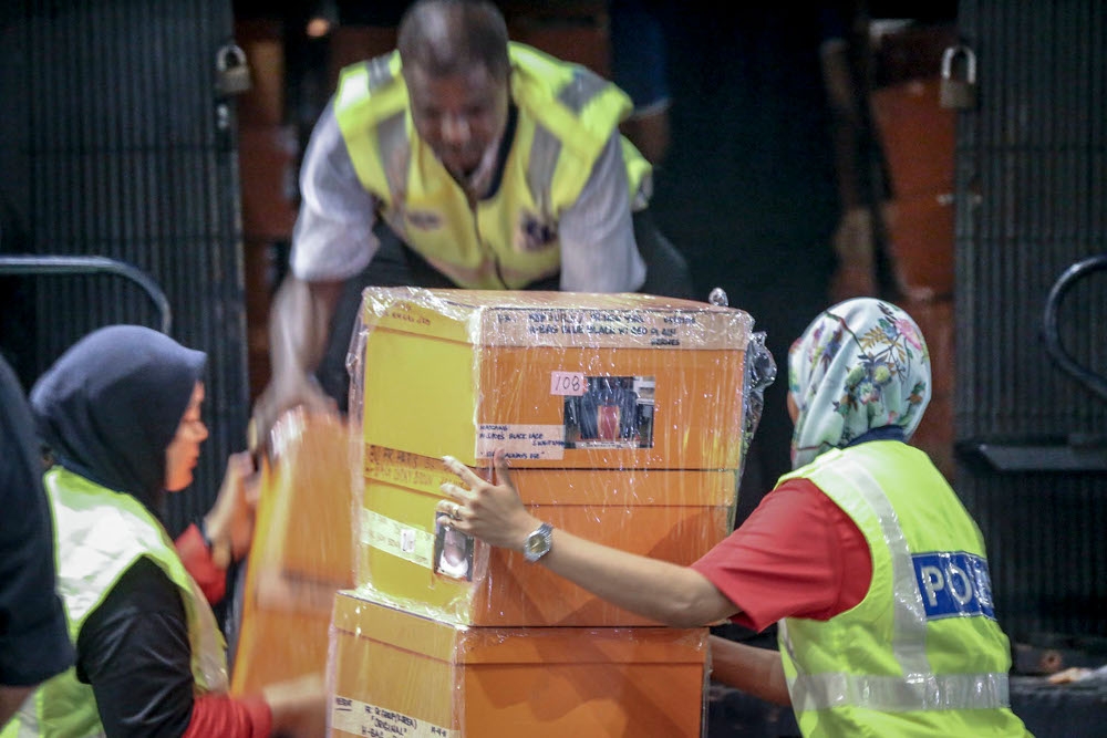 File picture of investigators lifting sealed boxes believed to contain luxury designer bags onto a Black Maria outside Pavilion Residences in Kuala Lumpur May 18, 2018. A total of 40 luxury handbags from various brands linked to the 1Malaysia Development Berhad (1MDB) financial scandal will be put up for auction, said Datuk Seri Azalina Othman Said today. — Picture by Hari Anggara  