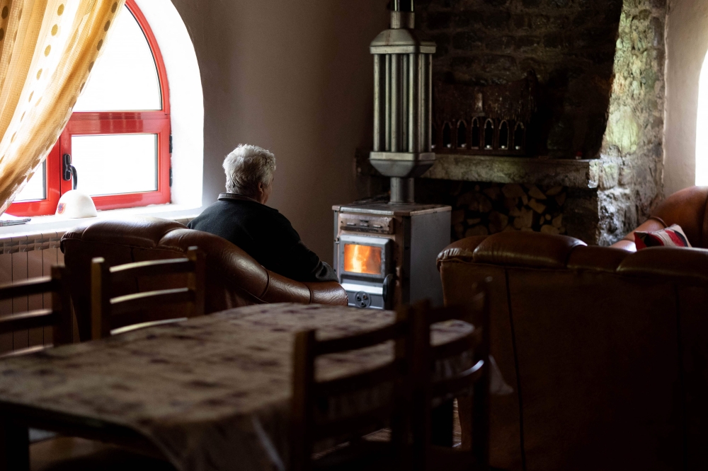 Grisha sits in front of a fire in her home. — AFP pic