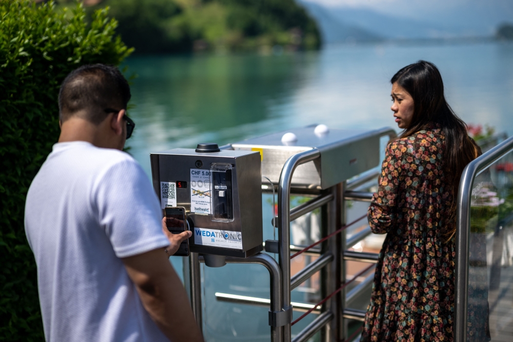 A tourist pays with his mobile to enter the famous pier. — AFP pic